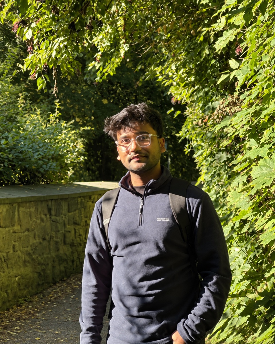 Abhisek Kumar standing on a sunlit garden path surrounded by green foliage